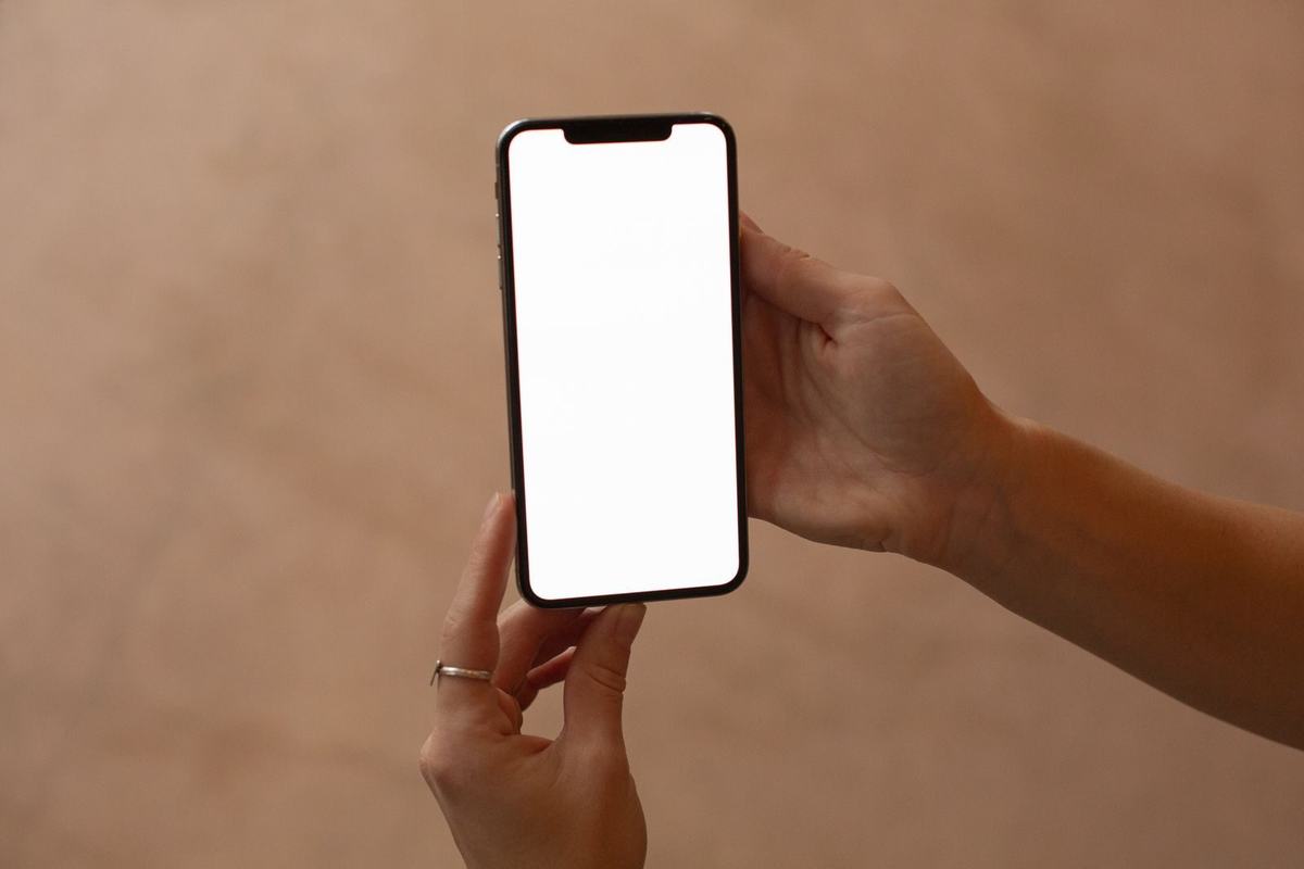 Dłoń trzymająca telefon z pustym ekranem
