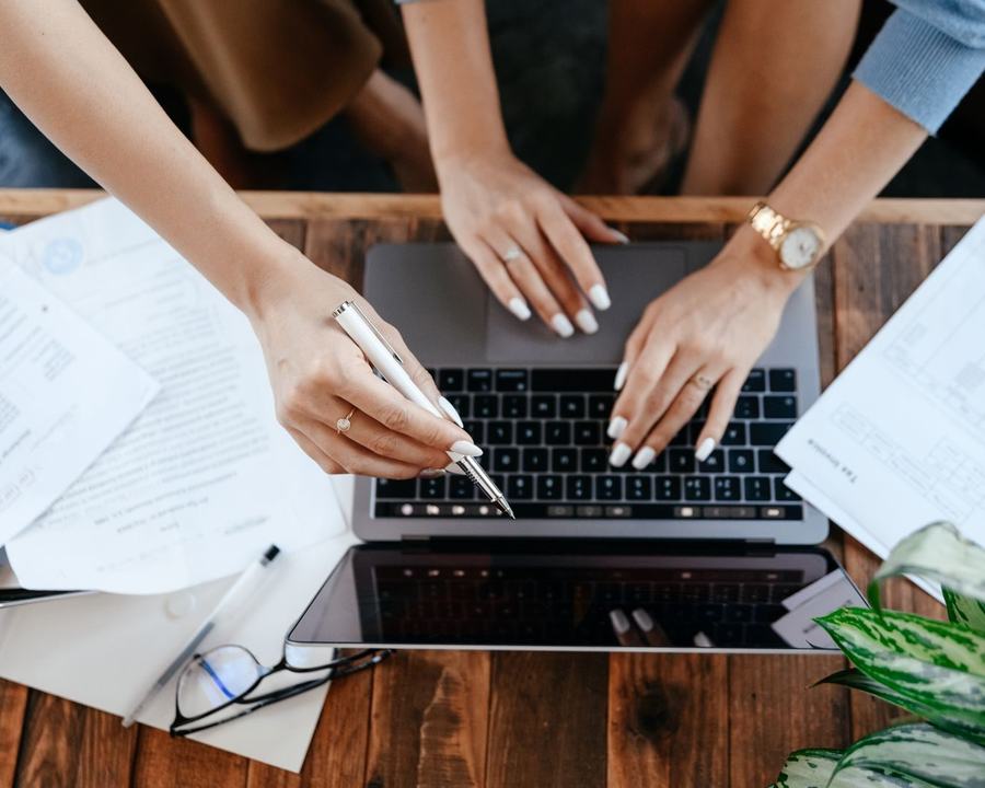 Ręce przy laptopie wśród dokumentów na biurku