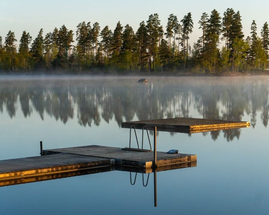 Drewniany pomost na spokojnym jeziorze otoczonym lasem